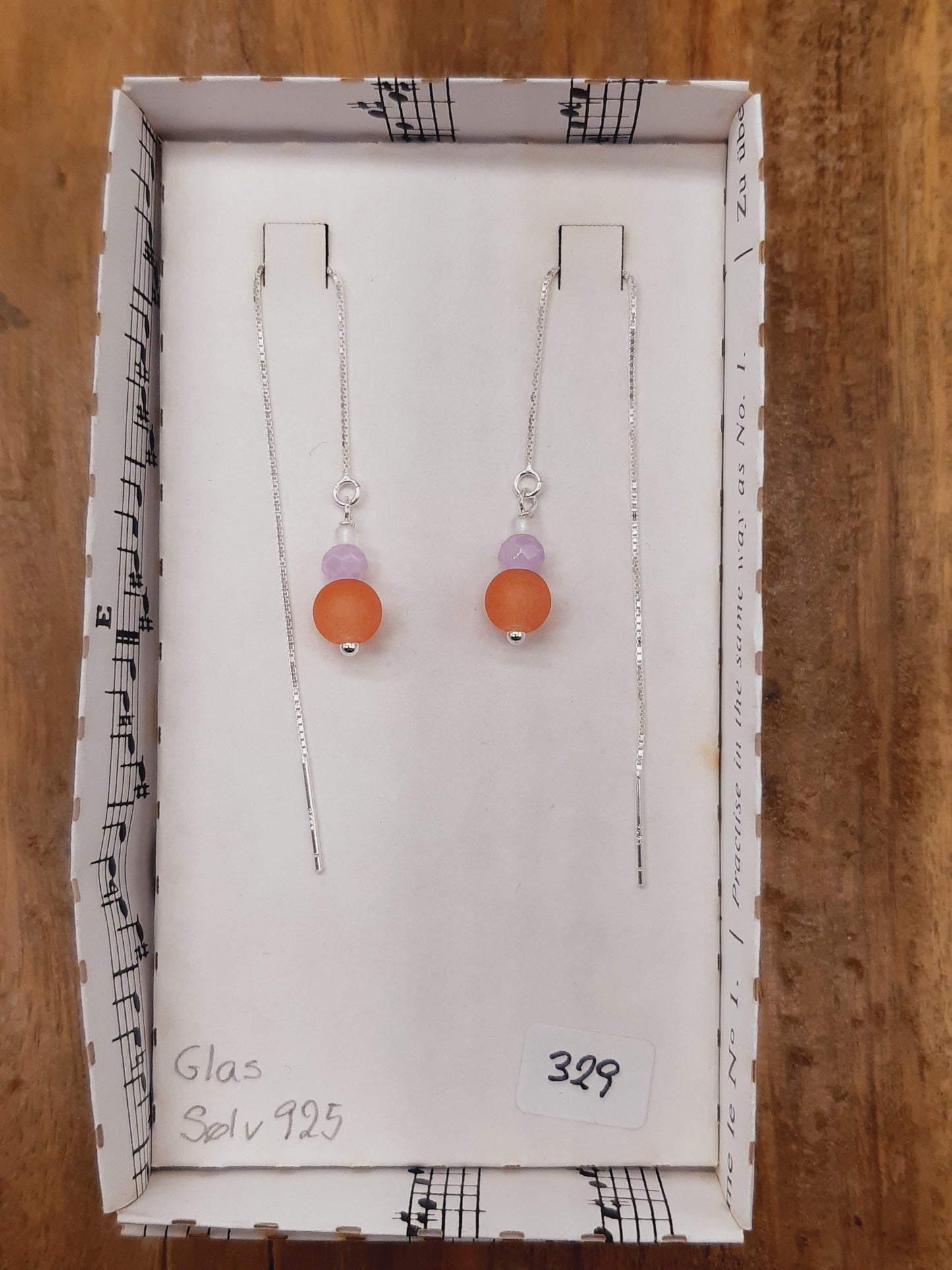 Orange, lys lilla og hvid glas i tråd