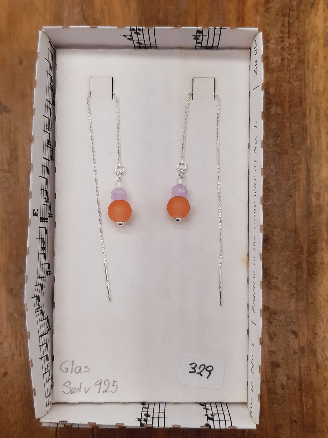 Orange, lys lilla og hvid glas i tråd